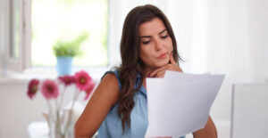 Mulher analisando documentos para Declaração de Imposto de Renda e organização dos comprovantes necessários