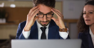 Profissional preocupado diante do computador ilustrando Erros Mais Comuns na declaração de Imposto de Renda
